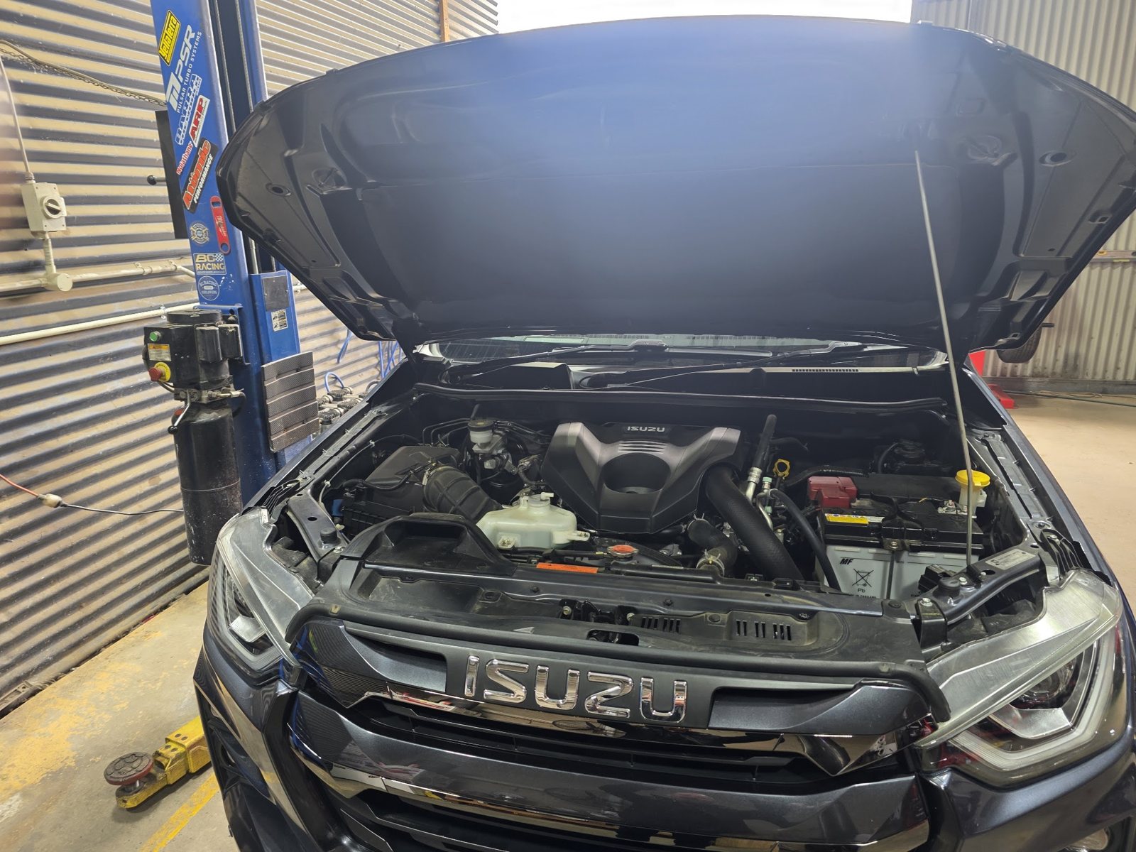 Black Isuzu D-Max with the bonnet up in the workshop bay