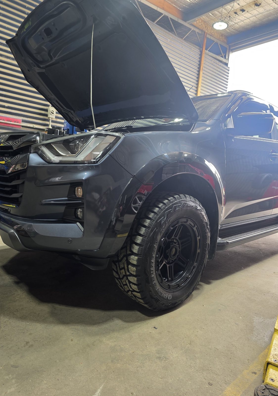 Lifted grey Isuzu D-Max dual cab with off road tyres, bonnet up in the workshop bay