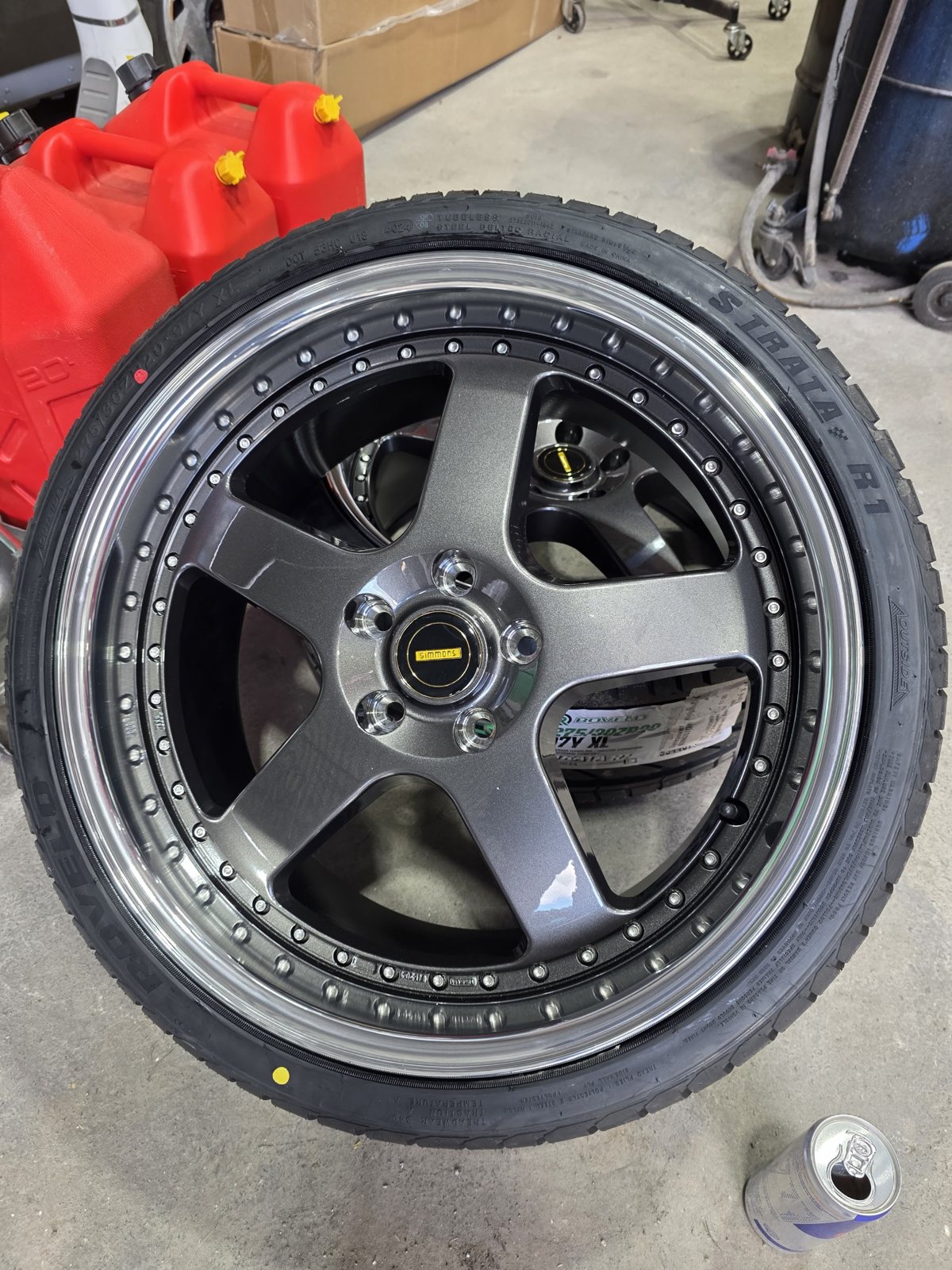 A new tyre freshly fitted to a five spoke alloy wheel on the workshop floor